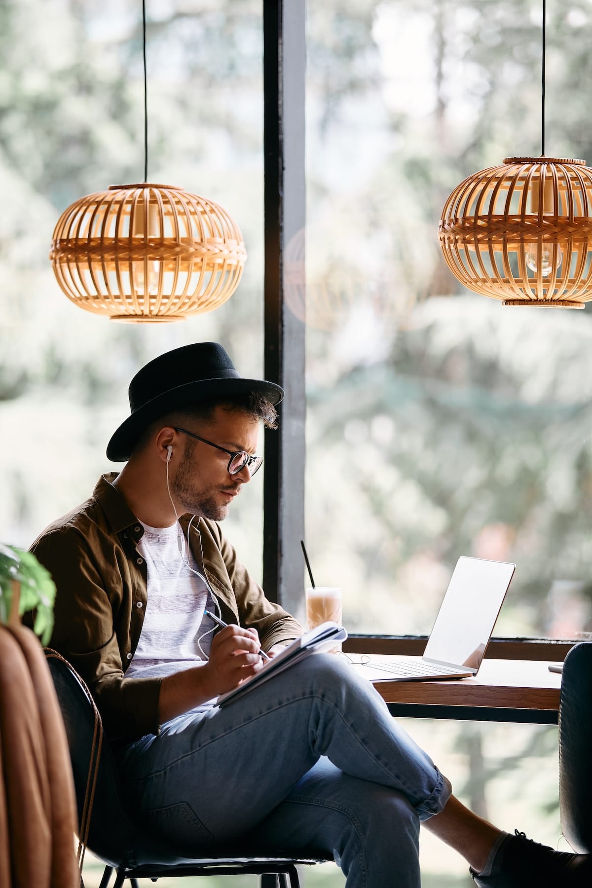 chico sentado en una cafeteria con portatil tomando notas mejores recursos para aprender ingles